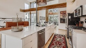A modern kitchen with a large island, stainless steel appliances, and a red patterned rug. - Spacious Retreat for Groups W/Workspace Min to DT & SXSW Top Spots! (Austin)