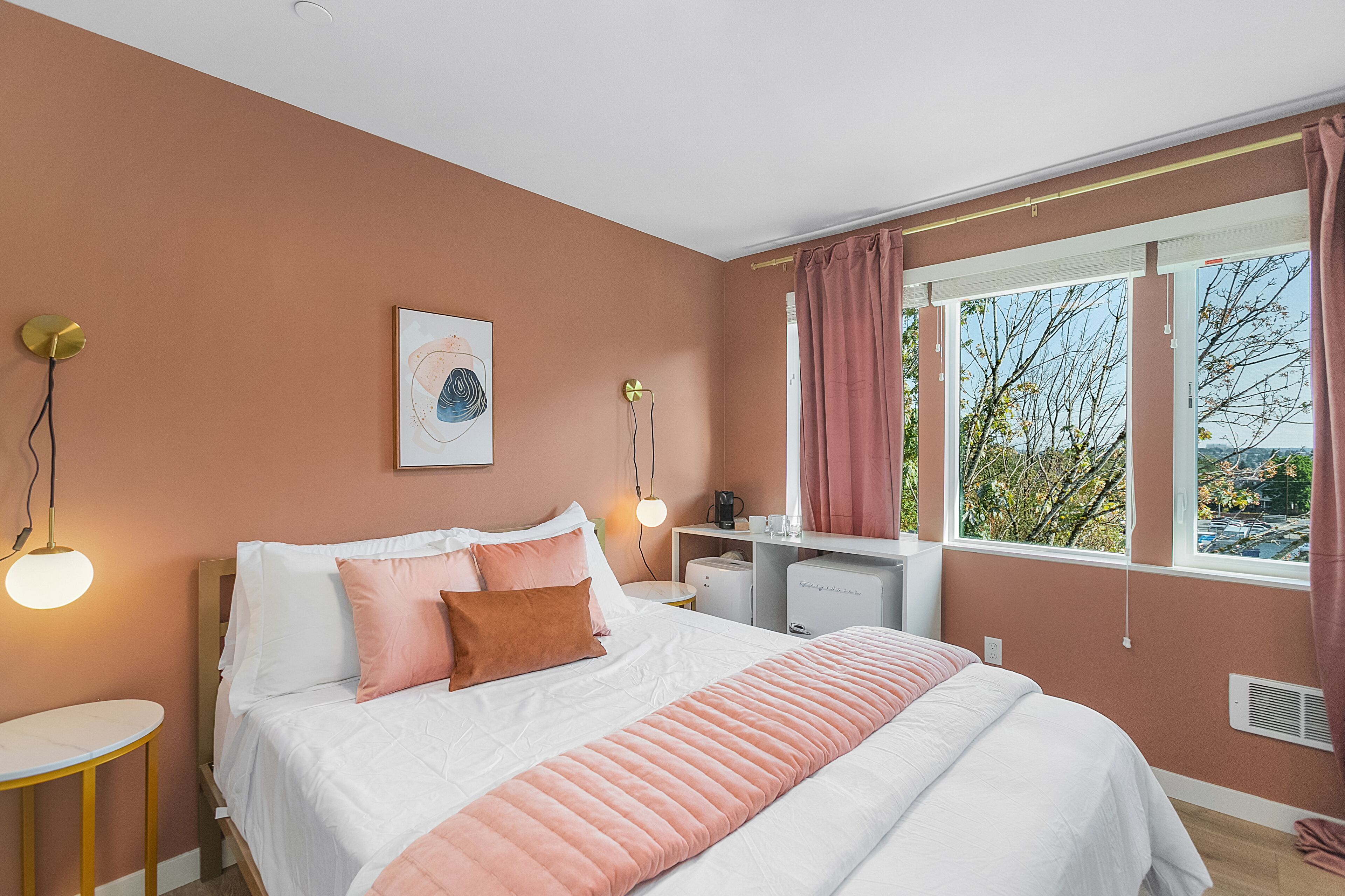 A bedroom with a bed, bedside tables, a desk, and a window with curtains.