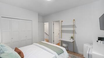 A modern bedroom with a bed, white wardrobe, and a small desk area with a chair.