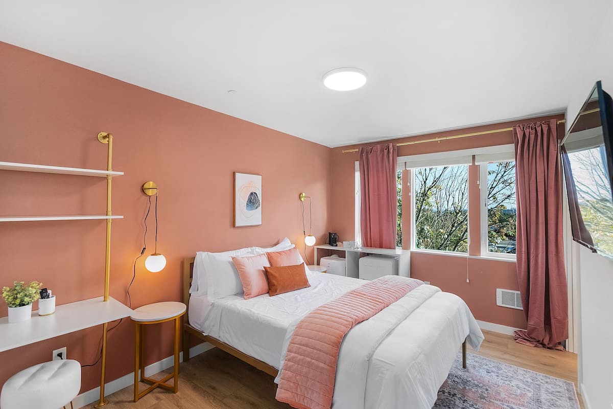 A bedroom with a bed, bedside tables, a desk, and a window with curtains.