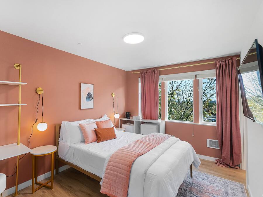 A bedroom with a bed, bedside tables, a desk, and a window with curtains.