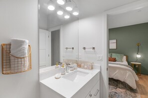 A modern bathroom with a white vanity, a large mirror, and a towel rack. - Sweet Suites Capitol Hill (Seattle)