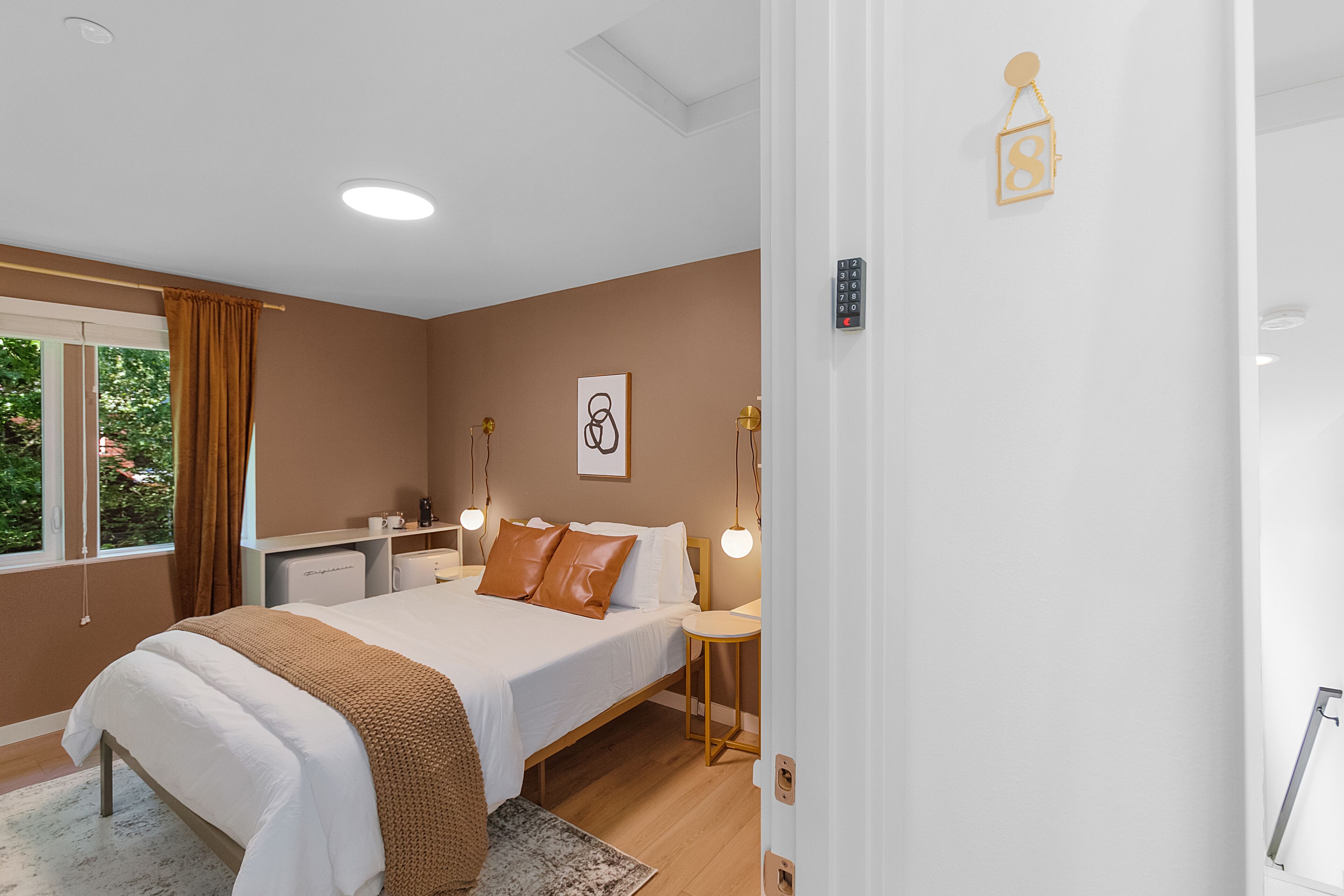 A bedroom with a bed, bedside tables, a nightstand, a desk, and a window with curtains.
