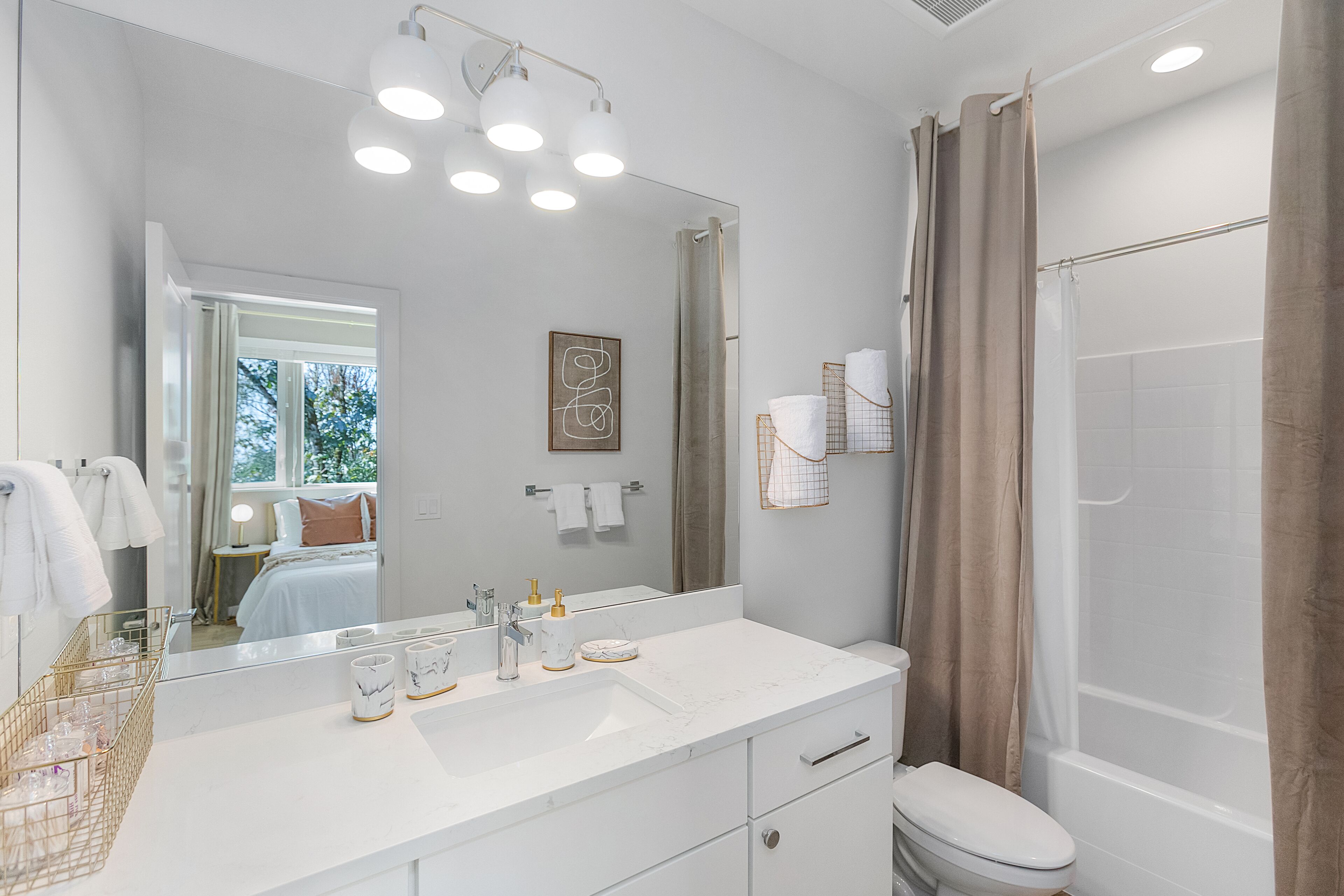 Une salle de bain moderne avec un grand miroir, un meuble-lavabo blanc et un espace douche.