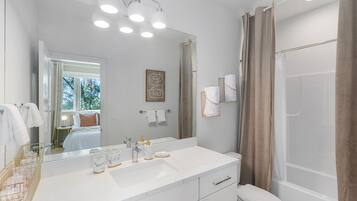 Une salle de bain moderne avec un grand miroir, un meuble-lavabo blanc et un espace douche.