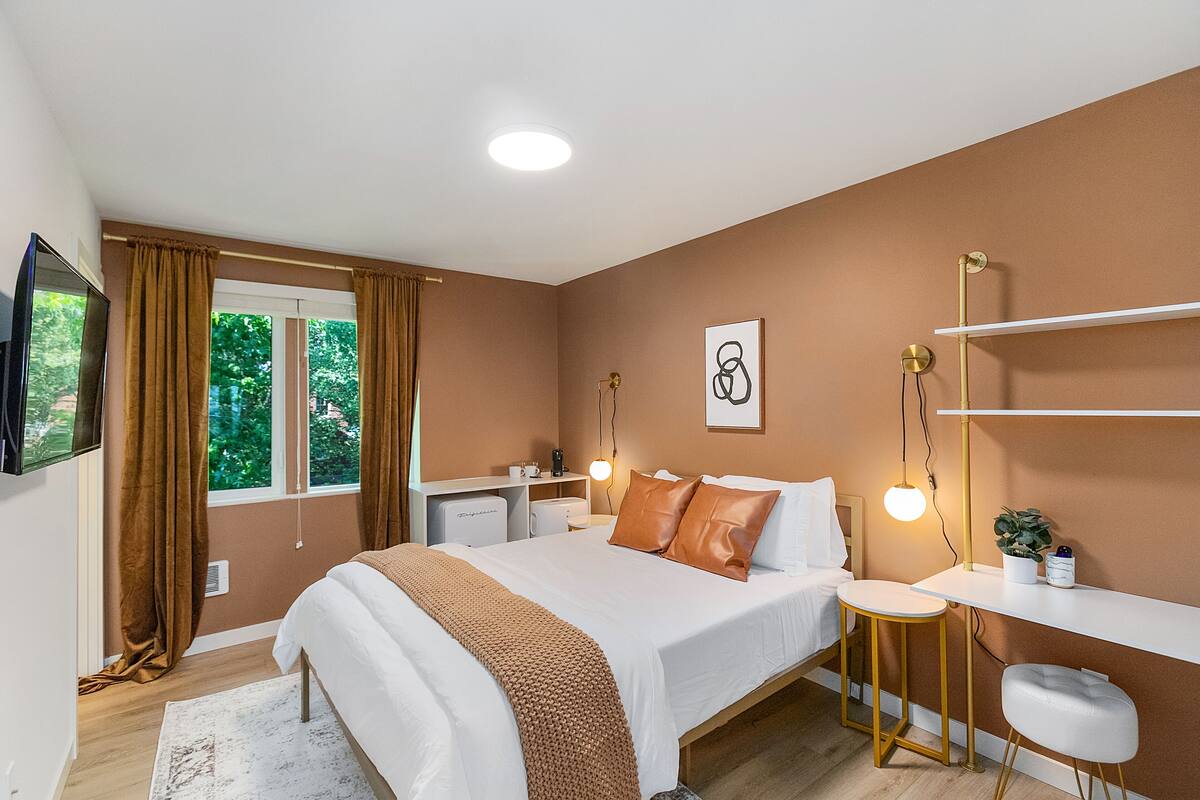 A modern bedroom with a bed, bedside table, desk, and chair.