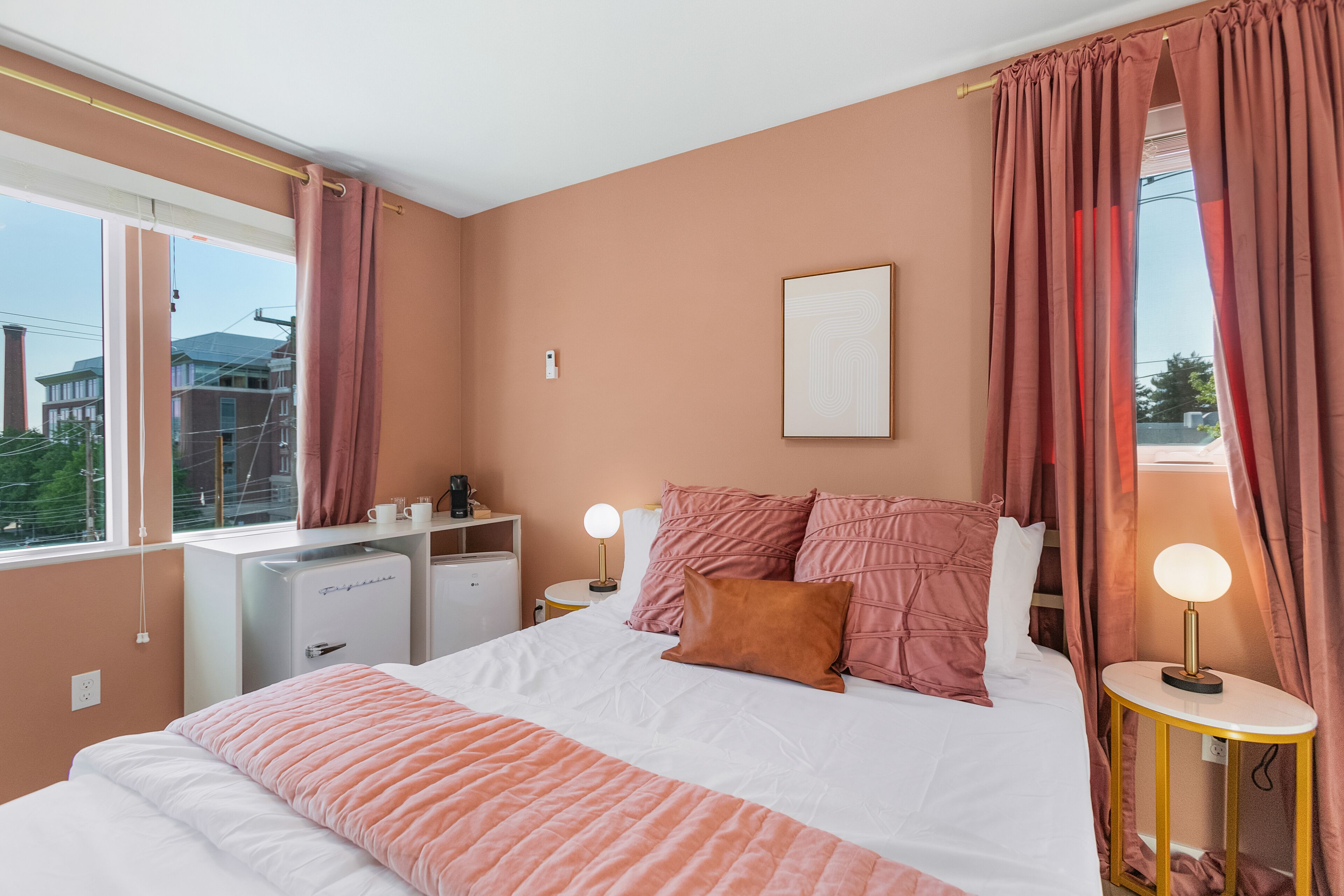 A bedroom with a bed, bedside tables, a desk, and a window.