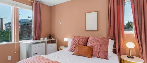 A bedroom with a bed, bedside tables, a desk, and a window.