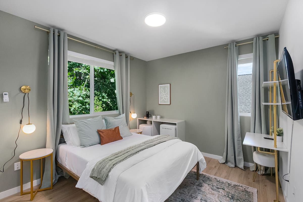 A modern bedroom with a large bed, bedside tables, a desk, and a TV.
