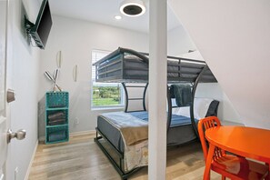 Una habitació amb lliteres, una taula petita i un televisor muntat a la paret.