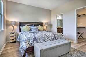 A bedroom with a large bed, bedside lamps, a nightstand, a bench, and a walk-in closet. - Family Home w/ Fenced Yard in Austin Suburbs! (Buda)