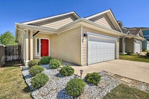 A single-story house with a red door, beige siding, and a white garage door.
