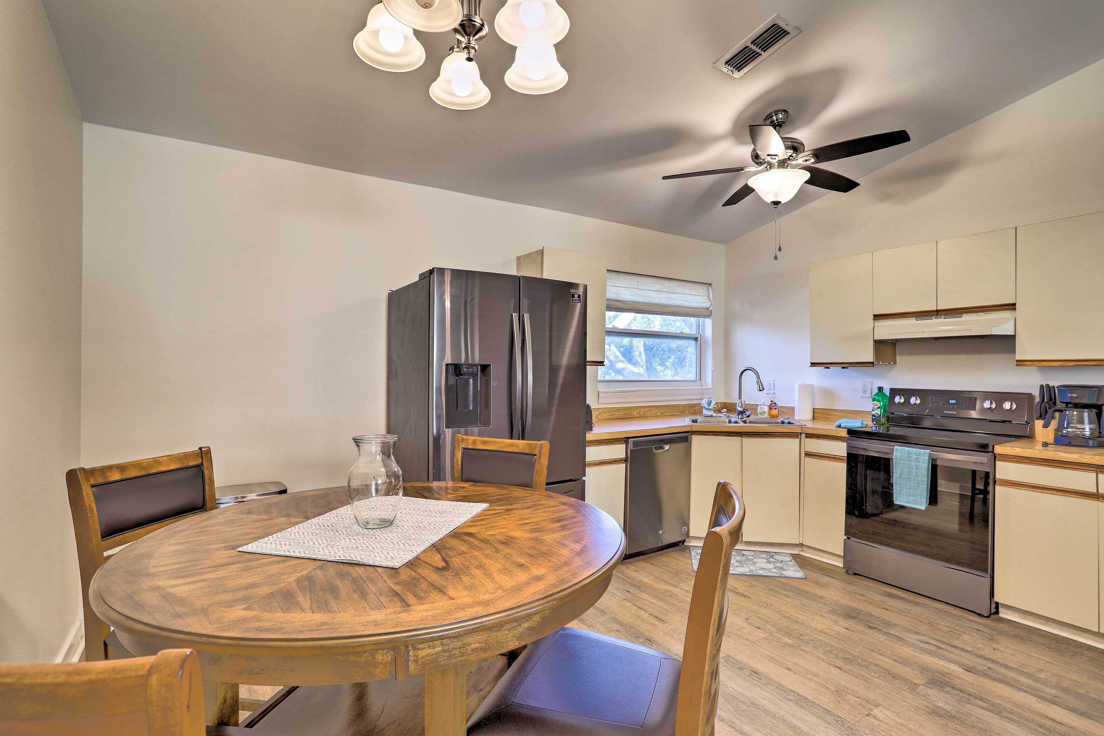 Una cucina moderna con un tavolo rotondo in legno, elettrodomestici in acciaio inossidabile e una ventola a soffitto.