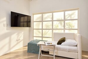 A room with a bed, a TV mounted on the wall, and a window with a view of trees.