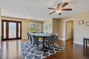 A spacious room with a pool table, ceiling fan, and a view of the outdoors through a glass door.