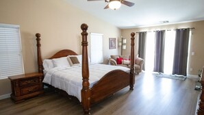 Ein Schlafzimmer mit Himmelbett, Nachttisch, Stuhl und Deckenventilator.
