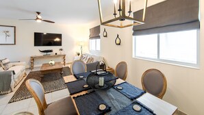 Un salon moderne comprenant un coin repas, un ventilateur de plafond, un téléviseur et une grande fenêtre.