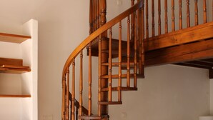 Una scala a chiocciola in legno in un soggiorno con un divano e una lampada.