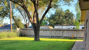 A grassy yard with a tree, a wooden fence, and a concrete path. - Quiet and comfortable Two Bedrooms, one Bathroom up to group of Four. (Mission)