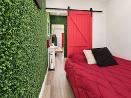 Een slaapkamer met een rood bed, een witte nachtkastje en een rode schuifdeur.