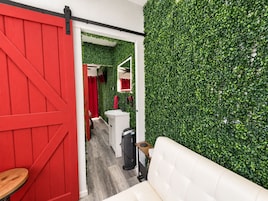 Een modern interieur met een rode schuifdeur, een groene wand, een witte bank en een badkamer met een rood douchegordijn.