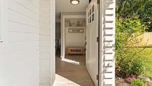 A narrow hallway with a wooden floor leading to a door with a 'WELCOME' sign. - Ridge View Retreat with Mtn Views & Hot Tub (Port Angeles)
