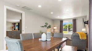 A dining area with a wooden table, grey upholstered chairs, and a patterned sofa. - Ridge View Retreat with Mtn Views & Hot Tub (Port Angeles)