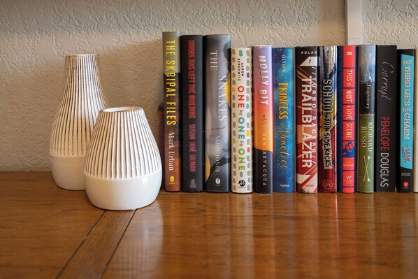 A row of books on a wooden surface with two white vases on the left. - Ridge View Retreat with Mtn Views & Hot Tub (Port Angeles)