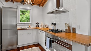 A modern kitchen with white cabinets, a wooden countertop, stainless steel appliances, and a window with a view of greenery.