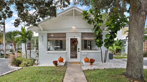 A small, single-story house with a white exterior, a front porch, and a visible number "633" on the door.