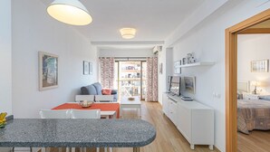 Un espace de vie compact comprenant une kitchenette, un coin repas et une chambre.
