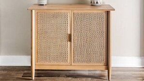 A wooden console with two doors, a mirror above it, and two decorative items on top.