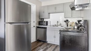 A modern kitchen with stainless steel appliances, white cabinets, and a wooden floor.