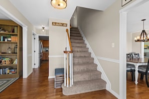 A staircase with a wooden handrail and carpeted steps leading to a dining area with a table and chairs.