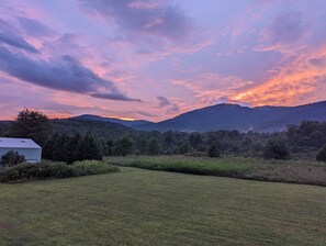 A grassy field with a white building and a mountain range in the background.