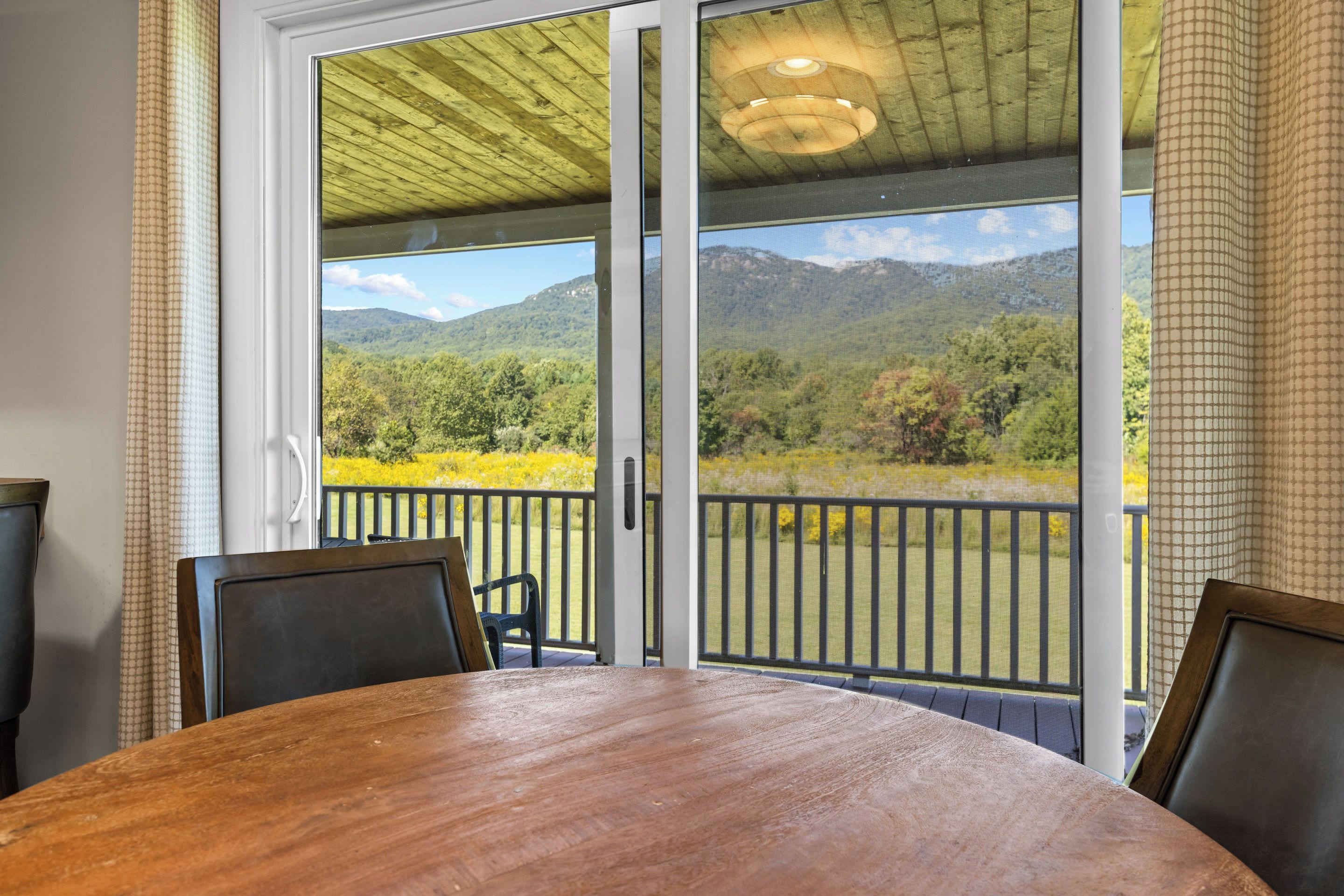 Une pièce dotée d’une grande porte-fenêtre coulissante donnant sur un balcon avec vue sur les montagnes.