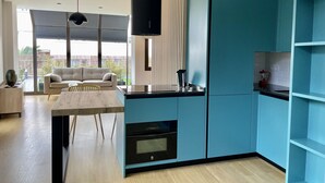 Une cuisine moderne avec des meubles de couleur turquoise, un four encastré et un coin repas comprenant une table et des chaises en bois.
