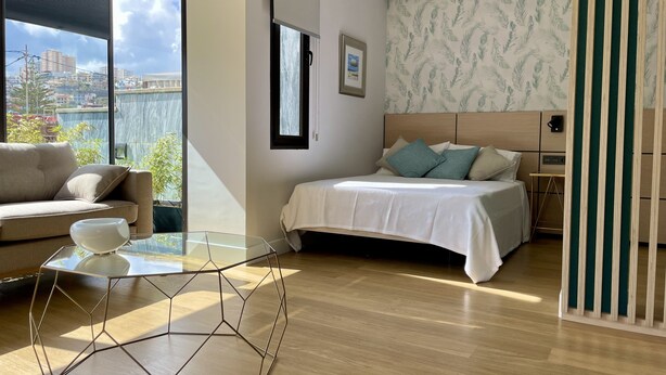 Une chambre moderne avec un lit, un canapé, une table en verre et une vue sur la ville.