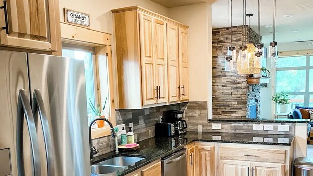 Una cocina moderna con armarios de madera, electrodomésticos de acero inoxidable y un protector contra salpicaduras de piedra.
