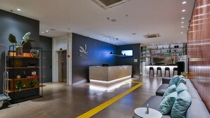 Een moderne hotellobby met een receptiebalie, zithoek en een bar.