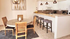 A modern kitchen with white cabinets, a central island with bar stools, and pendant lighting. - BEST LOCATION on Grace Bay! The Plaza at Ocean Club West! No Car Needed! (Grace Bay)
