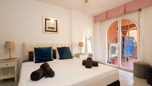 Habitación de hotel con una cama grande, dos mesitas de noche, un espejo y una puerta corrediza de vidrio que da a un espacio al aire libre.