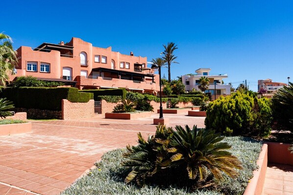 Zona residencial con un edificio de varios pisos, senderos pavimentados y jardines ajardinados.