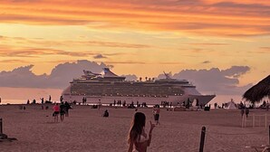 Un crucero amarrado en una playa con un atardecer al fondo.