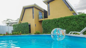 Un edificio moderno con un diseño arquitectónico único, una piscina y un cielo despejado.