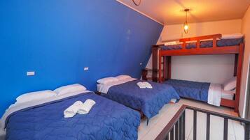 A room with two bunk beds, a blue wall, and a small staircase.