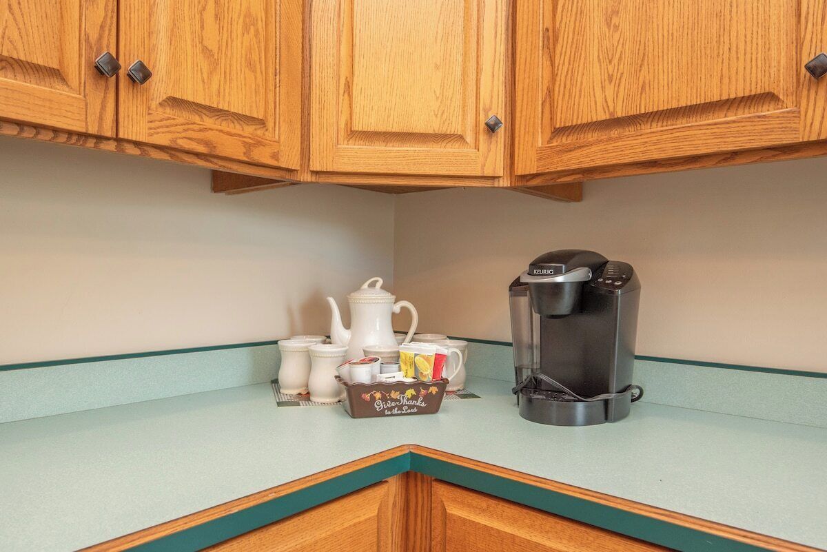 Una cocina con armarios de madera, una cafetera y un juego de tazas sobre la encimera.