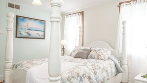 Un dormitorio con cama con dosel, un cuadro en la pared y una mesita de noche con lámpara.