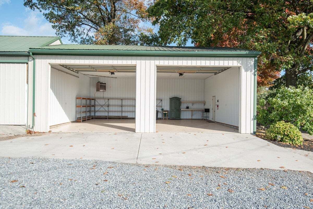 A covered outdoor area with a concrete floor, metal fencing, and a green roof.