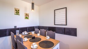 Un comedor con una mesa de madera, sillas tapizadas en gris y una lámpara colgante.